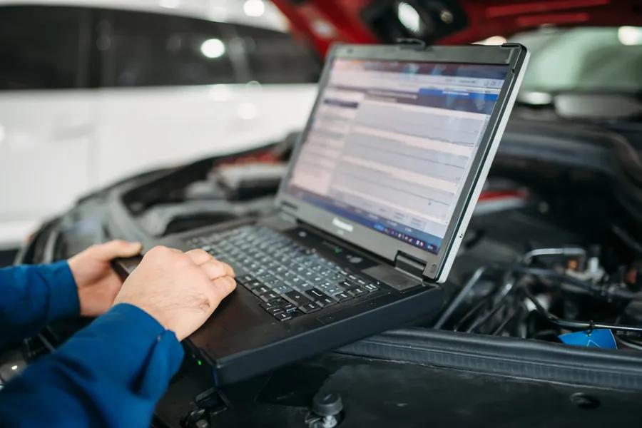 Fahrzeugdiagnose mit Laptop im Motorraum
